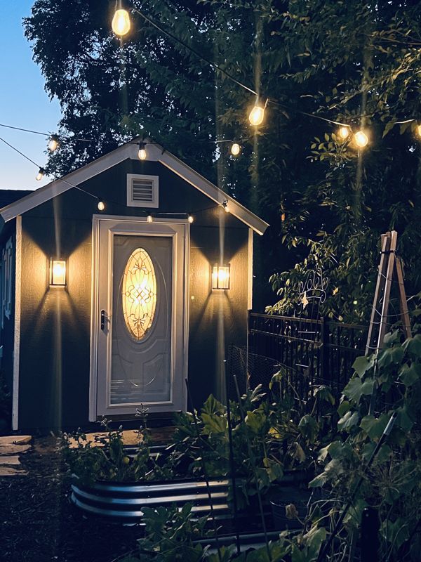 The Aubretta studio shed at night, string lights and a lit doorway